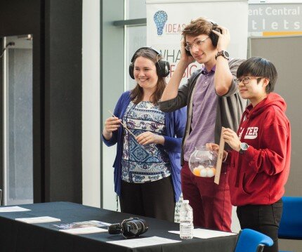 Haiyan, Pavel and Pam holiding a ruler and wearing headphones